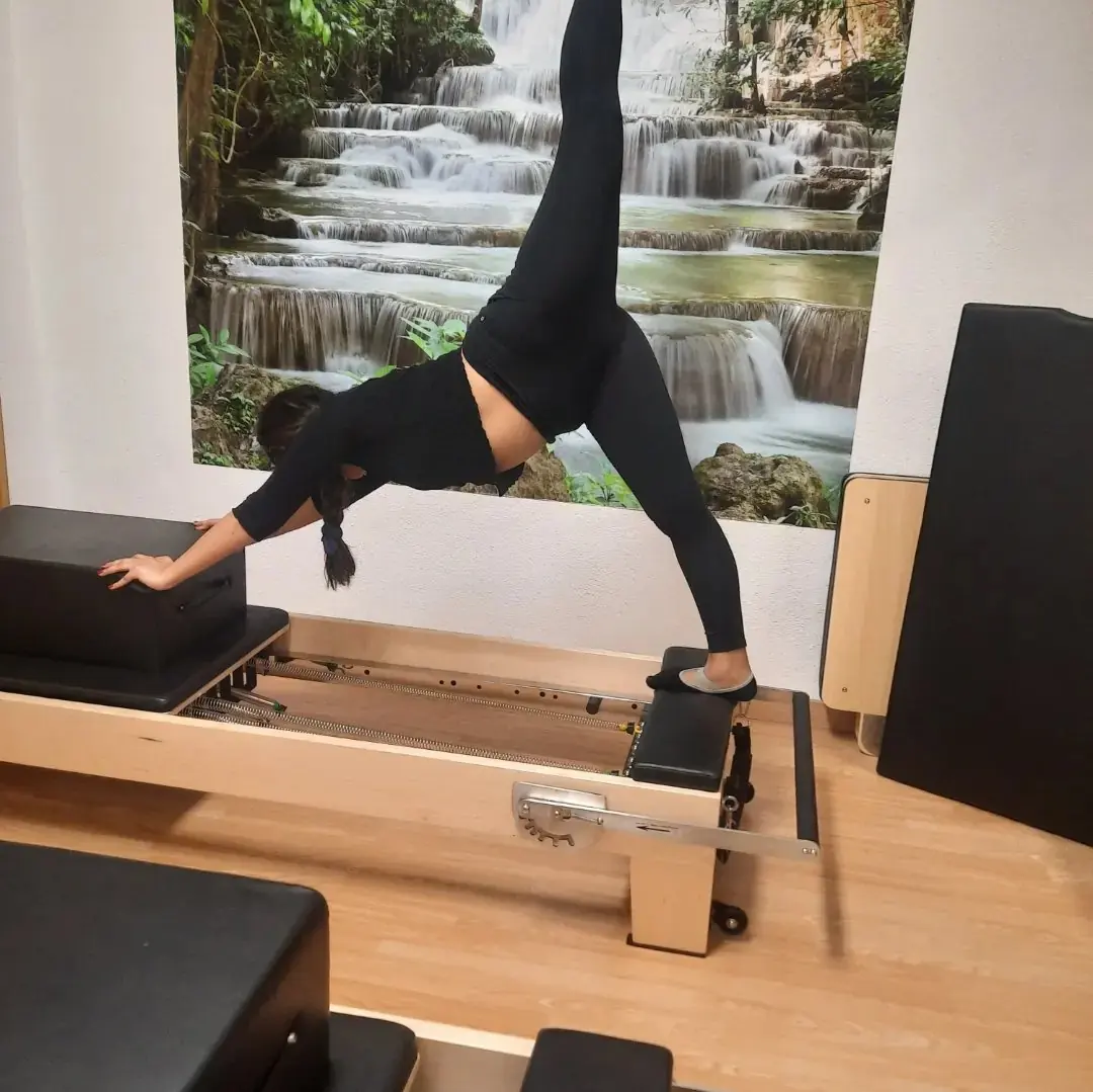 Estiramiento sobre el Reformer en la sala del mural